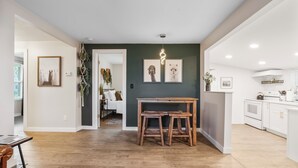 A modern kitchen with white cabinets, a wooden dining table, and a hanging light fixture. - Quiet get away in a vibrant city. (St. Augustine)
