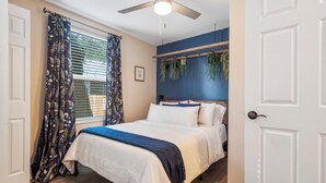 A bedroom with a bed, a ceiling fan, a window with curtains, and a wall-mounted plant. - Quiet get away in a vibrant city. (St. Augustine)