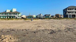 A beachfront property with multiple buildings, including a large house with a balcony and a smaller structure with a staircase. - Enjoy all the history and charm of Galveston Island - a block from the beach! (Galveston)