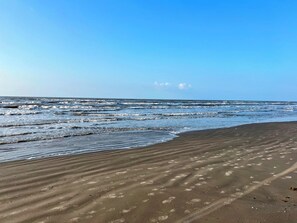 Una playa con huellas marcadas y olas.