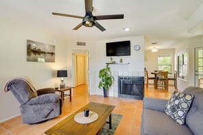 A living room with a sofa, armchair, coffee table, fireplace, TV, and a ceiling fan.