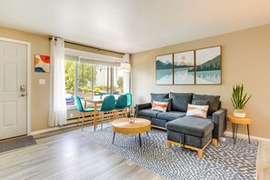A modern living room with a grey sofa, teal chairs, a wooden coffee table, and a patterned rug. - Seattle Scandi-Boho Gem: Walk to Waterfront! (Seattle)