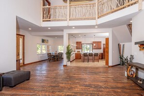 A spacious interior with a high ceiling, a dining area, kitchen, and a staircase leading to an upper level. - NEW 7500 sf, 5BR/7BA/Basement within walking distance to the Clark Fork river. (Thompson Falls)