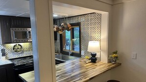 Una cucina moderna con un piano di lavoro in legno, elettrodomestici in acciaio inossidabile e vista all'esterno.