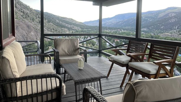 Zona relax all'aperto riparata, con mobili in vimini e vista su un paesaggio montuoso.
