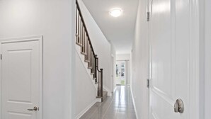 Ein Flur mit weißen Wänden, einer Holztreppe und einem Fliesenboden.