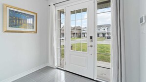 Eine weiße Tür mit Fensterglas, ein gerahmtes Bild an der Wand und ein Blick auf Häuser durch die Tür.