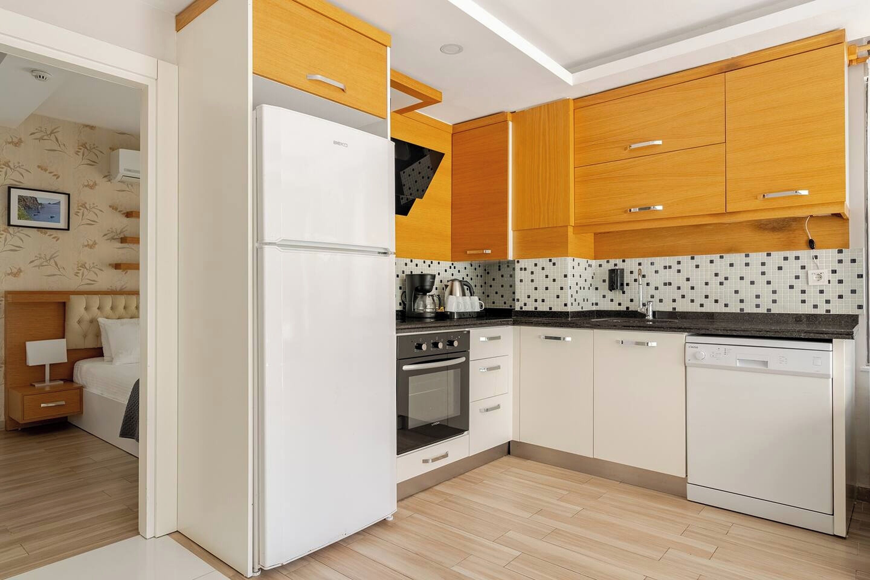 Une cuisine moderne avec des meubles blancs, un four encastré et un lave-vaisselle.