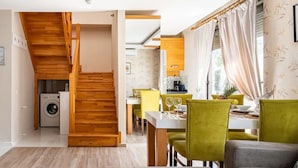 A modern kitchen with a dining area, wooden staircase, and a washing machine in the corner. - Loi Suite (Antalya)
