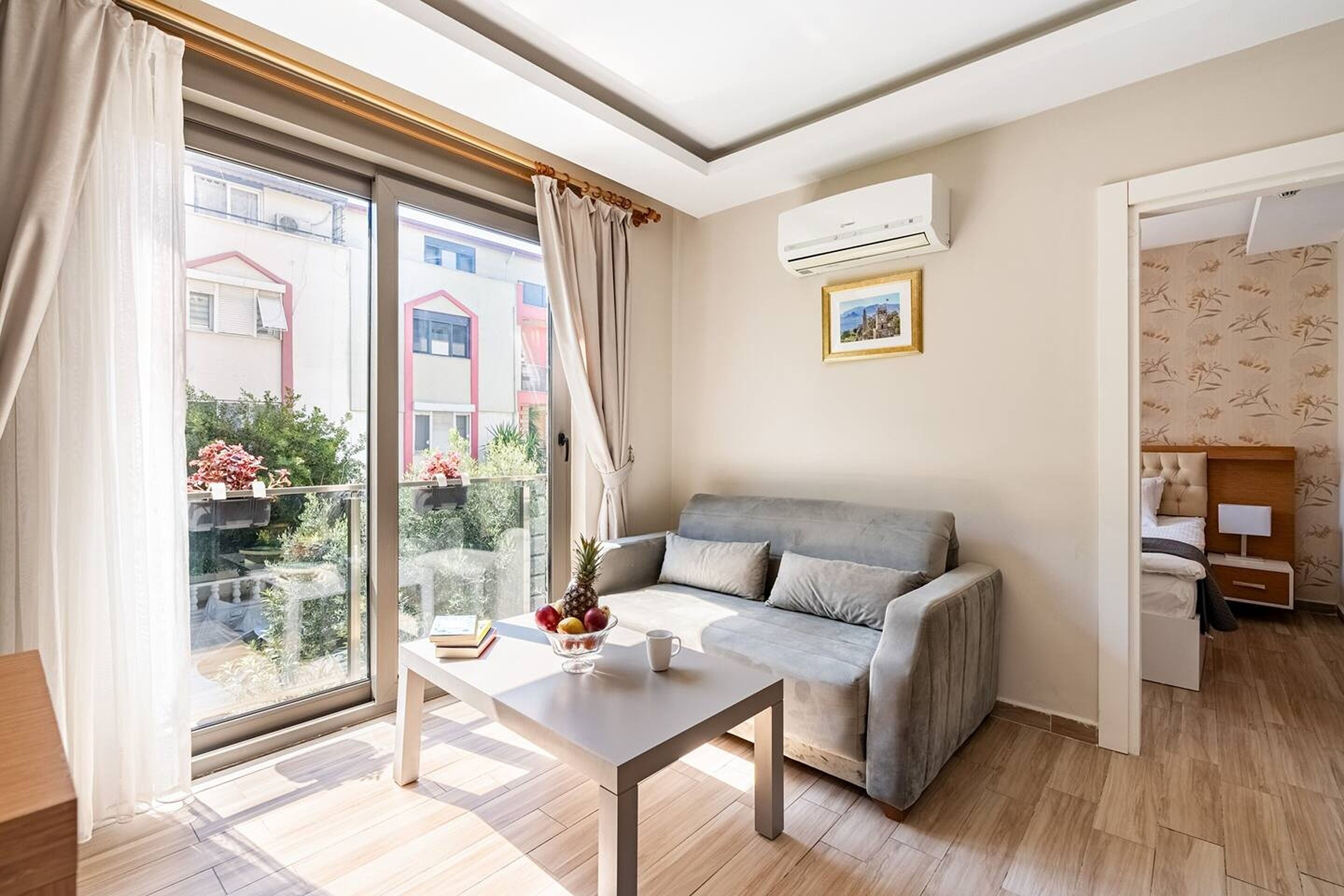 A modern living room with a sofa, a coffee table with fruit, and a view of buildings outside.