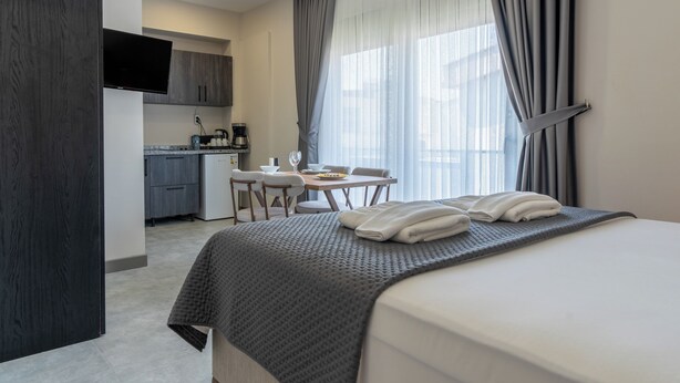 A hotel room with a bed, a desk, and a kitchenette. - Loi Suite (Antalya)