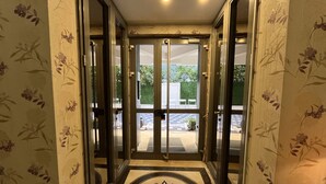 A hotel entrance with a double door, a tiled floor, and floral wallpaper. - Loi Suite (Antalya)