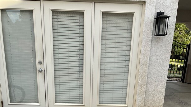 Ein Gebäude mit drei Glastüren, einer Steinterrasse und einem kleinen, runden Steinbecken.