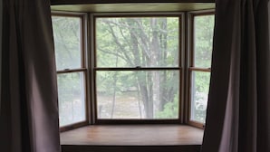 A bay window with a view of a forested area.