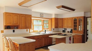 A spacious kitchen with wooden cabinets, a large island, and a window providing natural light.