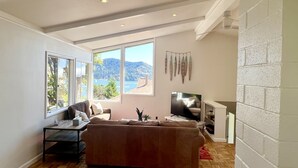 Una sala de estar con un ventanal grande, un sofá, un televisor y una chimenea.