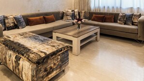 Ein modernes Wohnzimmer mit einer Eckcouch, einem Couchtisch und einem gemusterten Ottoman.
