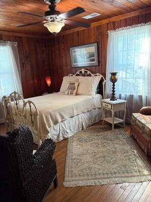 A wooden-paneled bedroom with a bed, bedside table, lamp, and a rug. - Adorable 2 story lake front setting. (Georgetown)