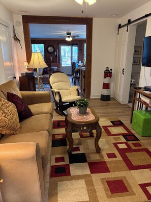 A living room with a beige sofa, a wooden coffee table, and a patterned rug. - Adorable 2 story lake front setting. (Georgetown)