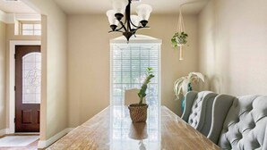 A dining room with a long wooden table, a chandelier, and a grey upholstered chair. - Feel At Home in Richmond (Richmond)