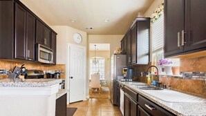A kitchen with dark cabinets, granite countertops, a microwave, and a sink. - Feel At Home in Richmond (Richmond)