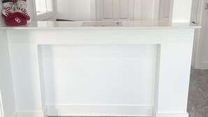 Een modern, minimalistisch interieur met een wit receptiebalie en een grijze deurmat met een motiverende boodschap.
