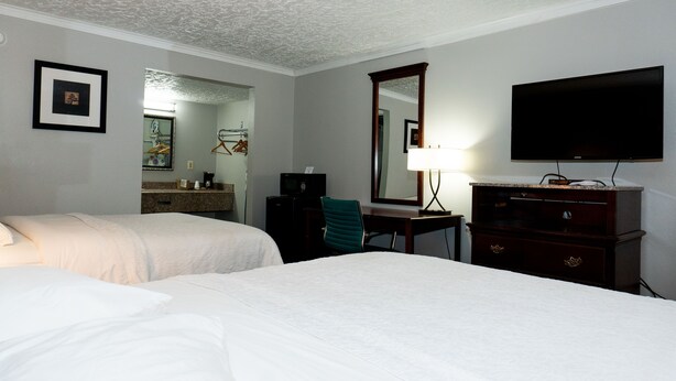 Een hotelkamer met twee bedden, een bureau, een televisie, een spiegel en een dressoir.