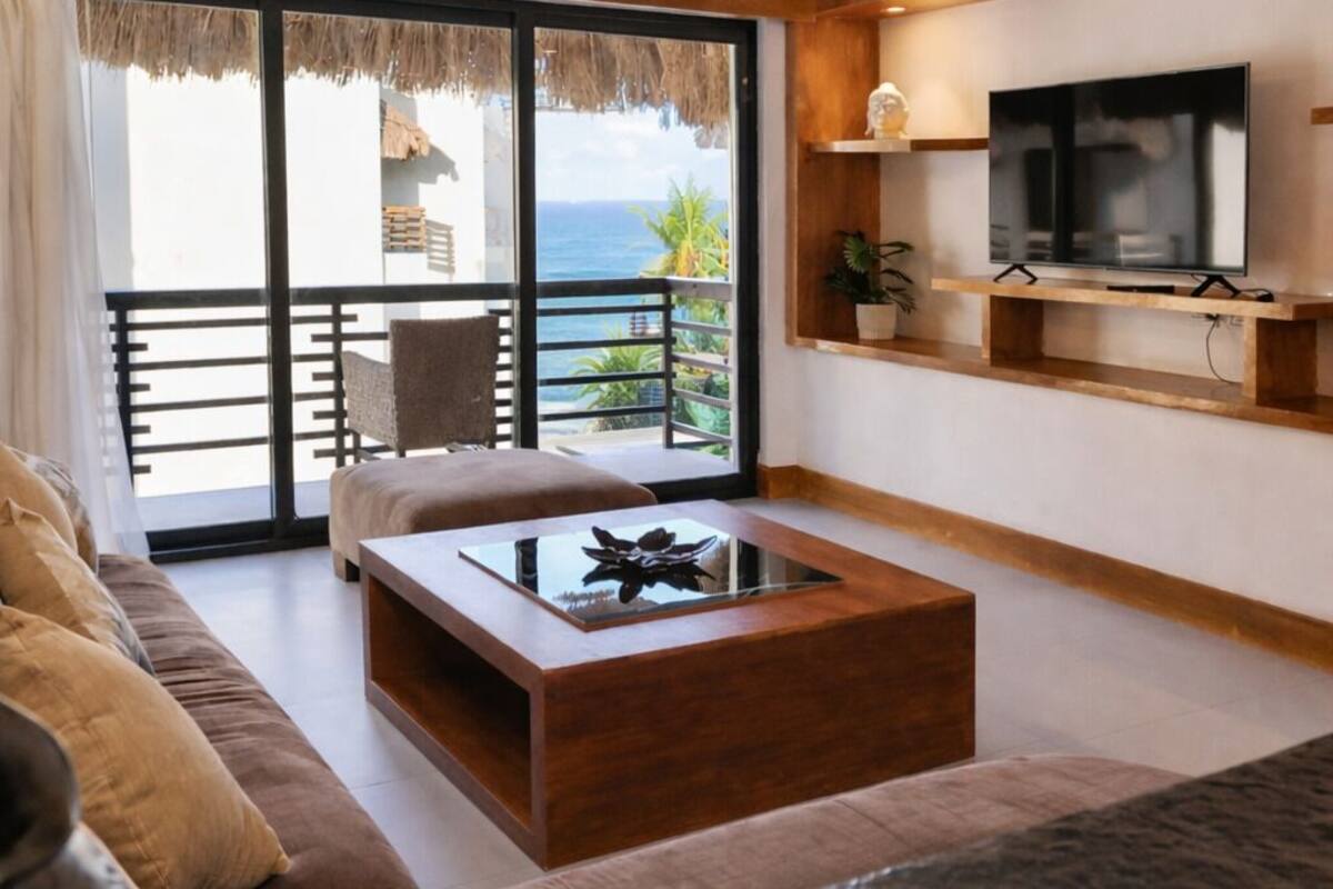 A modern living room with a large window, a flat-screen TV, a wooden coffee table, and a sofa.