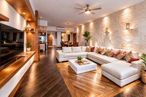 A modern living room with a large sectional sofa, a coffee table, and a TV on a wooden console.