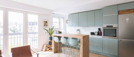 A modern kitchen with light blue cabinets, a wooden island, and a stainless steel refrigerator.