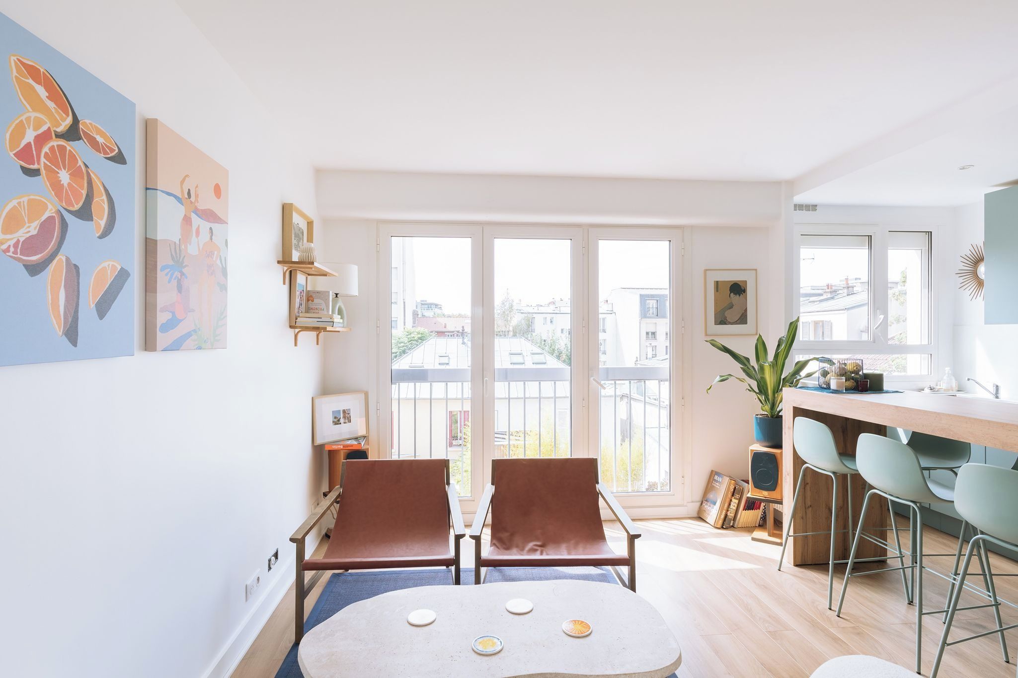 A modern apartment with a dining area, two chairs, a table, and a balcony with a view of buildings.