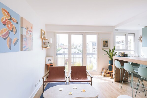 Un apartamento moderno con comedor, dos sillas, una mesa y un balcón con vistas a edificios.