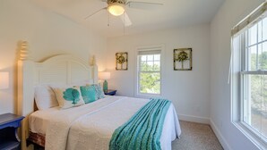 A bedroom with a bed, white walls, a ceiling fan, and two windows. - Near Ocean: Buxton Townhome w/ Patio! (Buxton)