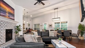 Un salón amplio con chimenea, un sofá modular, un comedor y un ventanal que proporciona luz natural.