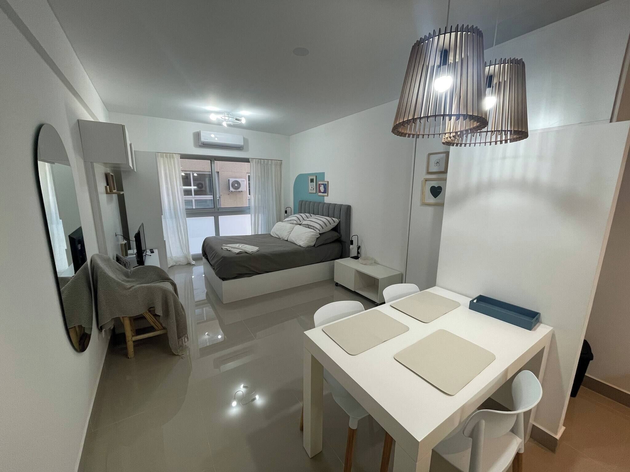 A modern bedroom with a bed, bedside table, and a desk with chairs.