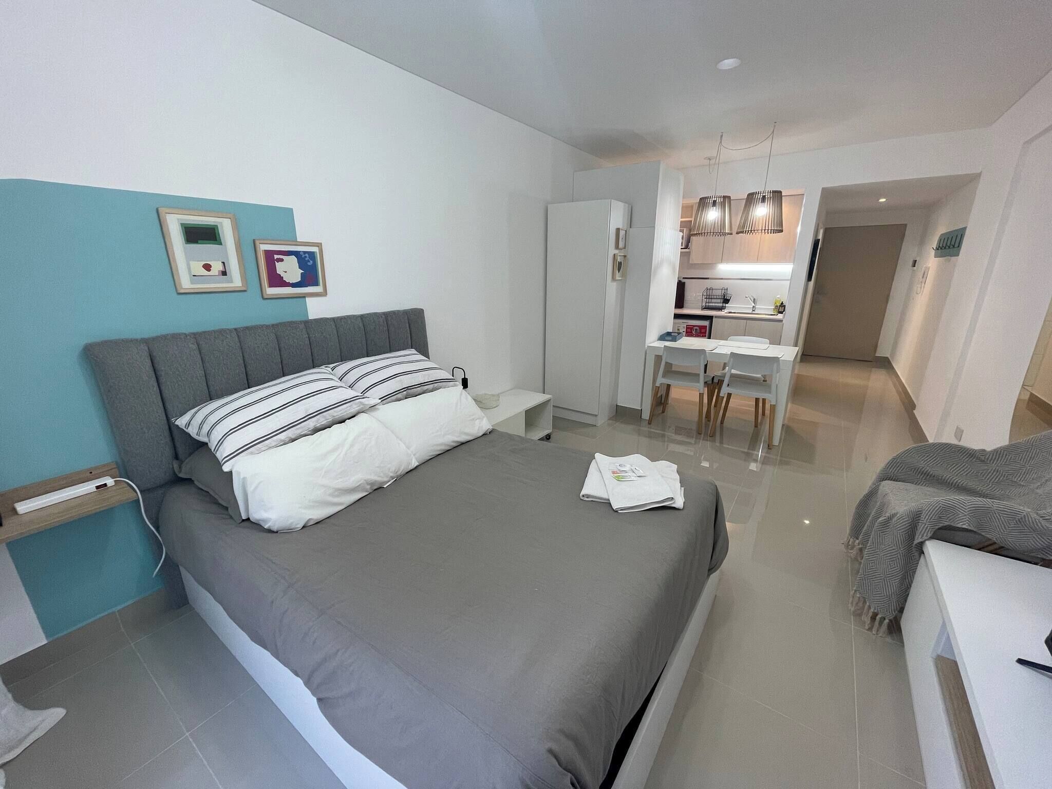 A modern bedroom with a bed, bedside table, and a small desk area with chairs.