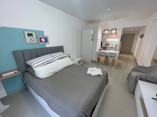 A modern bedroom with a bed, bedside table, and a small desk area with chairs.