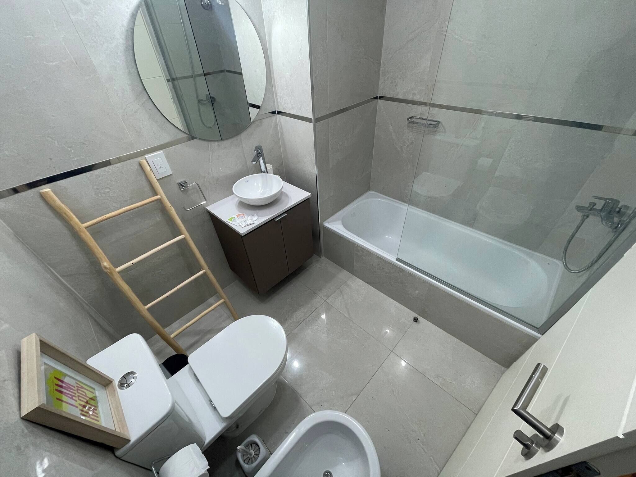 A modern bathroom with a toilet, bidet, sink, and bathtub.