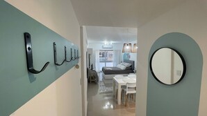 A hallway with a light blue wall, a black metal coat rack, and a round mirror on the right. - Modern Studio in San Telmo (Buenos Aires)