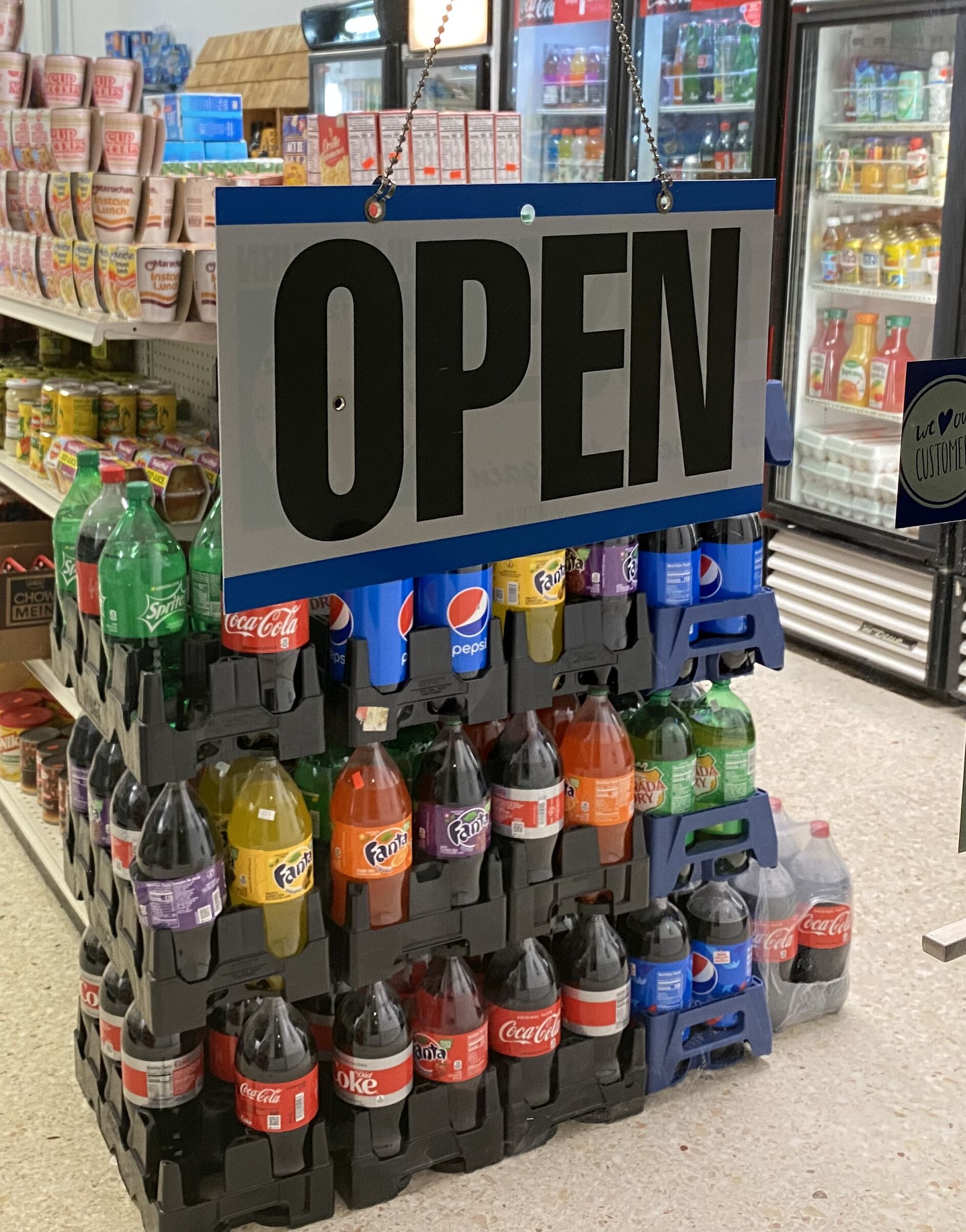 A beverage display with a prominent 'OPEN' sign, featuring various sodas and juices.