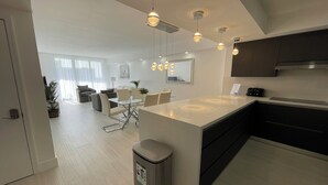 Une cuisine moderne dotée d’un îlot central, de luminaires suspendus et d’un coin repas avec un canapé et des chaises.