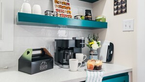 A modern kitchen with a coffee machine, a coffee cup, a box of baking supplies, and a menu sign.
