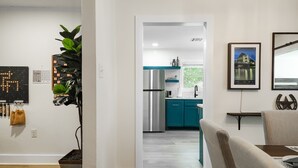 A modern kitchen with teal cabinets, a stainless steel refrigerator, and a window with a view of greenery.