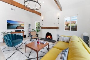 A living room with a fireplace, a sofa, a coffee table, and a TV. - Stylish 4bd/3bath - Spanish Home, central in LA (Los Angeles)