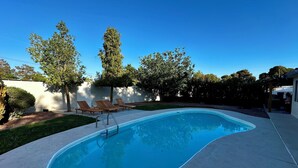 A swimming pool with a wooden deck, lounge chairs, and a pergola. - 🦚The Peacock Inn LV - 8 Bdr 4 Bth 14 Beds, Hi Speed WiFi (North Las Vegas)