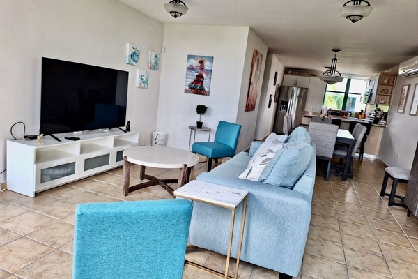 Large living room, sleep sofa and 65” 4K TV with dining room in the background.