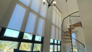 A high-ceiling room with large windows and a spiral staircase. - BEST AQUATIKA PENTHOUSE: truly beachfront, 10 beds, 5 rooms, 10 person capacity. (Vieques)