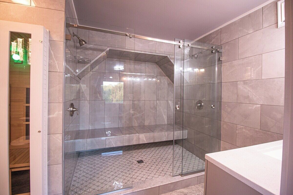 Une salle de bain moderne avec une douche à l’italienne, des carreaux de marbre et une baignoire.