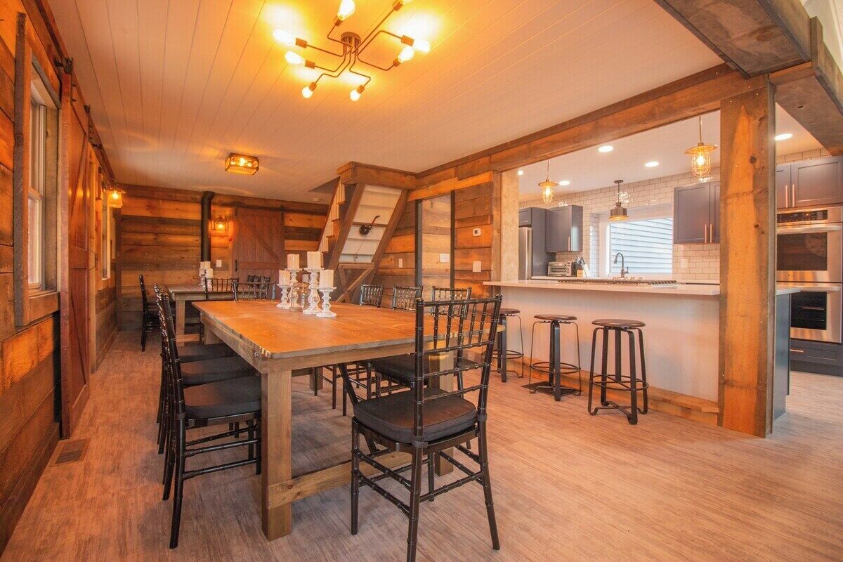 A cozy log cabin interior with a wooden dining table, chairs, and a kitchen area with modern appliances.
