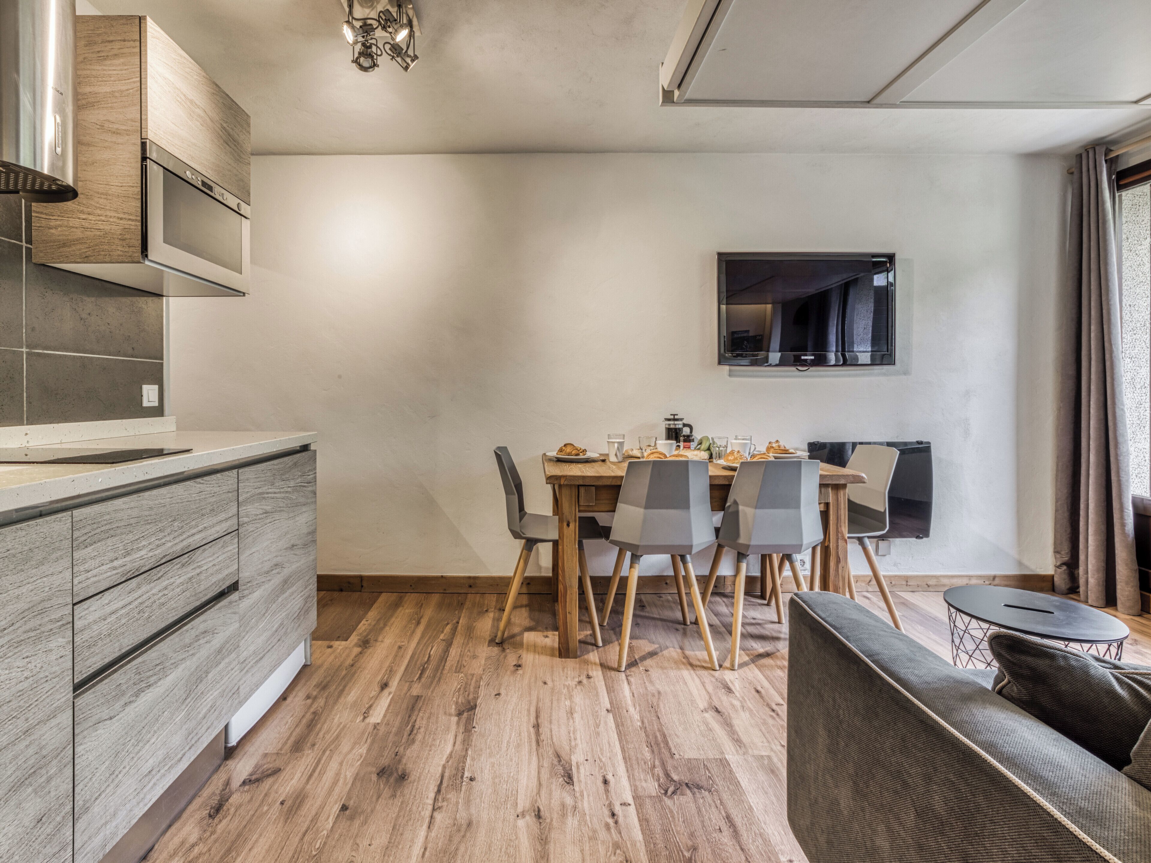 Een moderne keuken met houten kastjes en een eethoek met een tafel en stoelen.